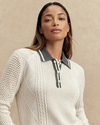 Woman wearing a white knit sweater with a gray collar against a beige background